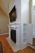 Convenient hidden storage cabinets tucked into the sides of the fireplace by Drumm Design Remodel