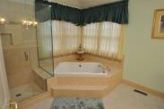 View from the hall into the bathroom corner tub and glass enclosed shower