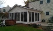 The Drumm Design Remodel version of this sun room features a peaked roof, a bank of energy efficient sliding glass doors, improved gutter system and a security spot light
